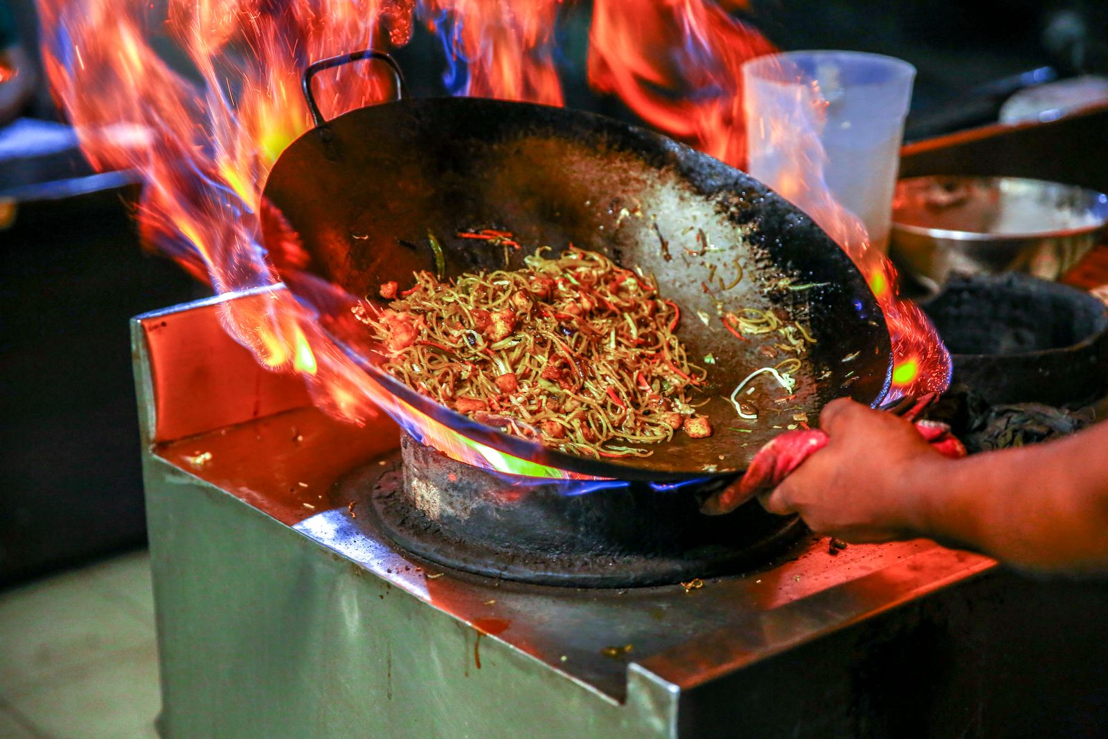 Chef cooking over a high gas flame in a restaurant kitchen