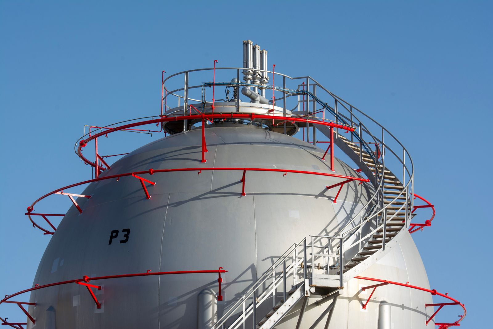 LPG storage sphere with access stairs against a clear sky